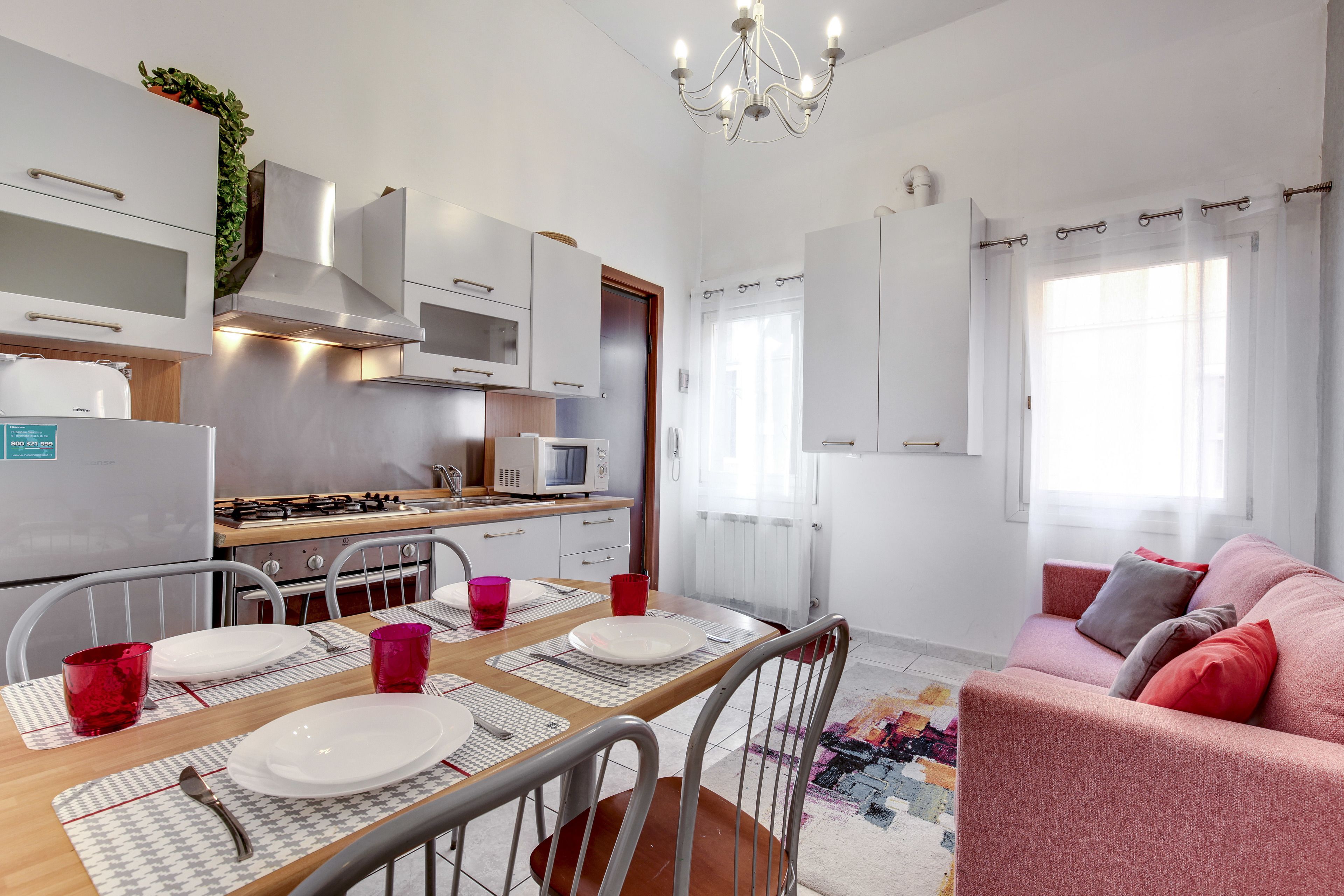 A modern kitchen with white cabinets, a stainless steel range hood, and a built-in microwave.