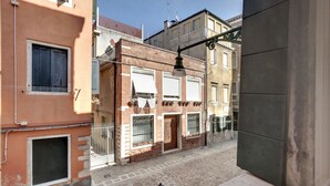 Una calle estrecha flanqueada por edificios con fachadas de ladrillo y enlucido, un pequeño espacio abierto con un hidrante y una barandilla metálica a lo largo de la calle.