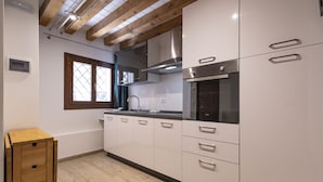 Una cocina moderna con armarios blancos, electrodomésticos de acero inoxidable y vigas de madera en el techo.