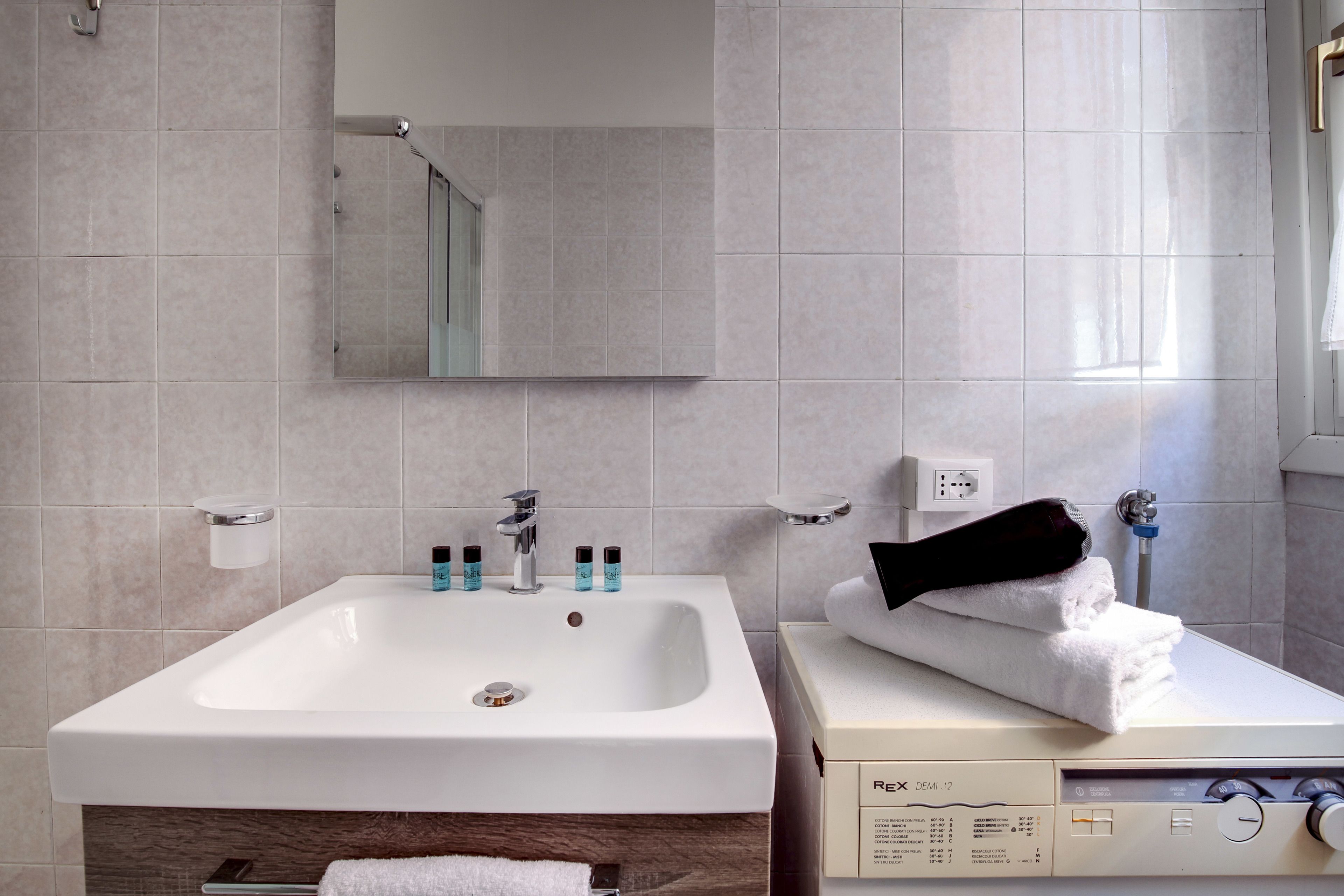 A modern bathroom with a white sink, mirror, and towel rack.