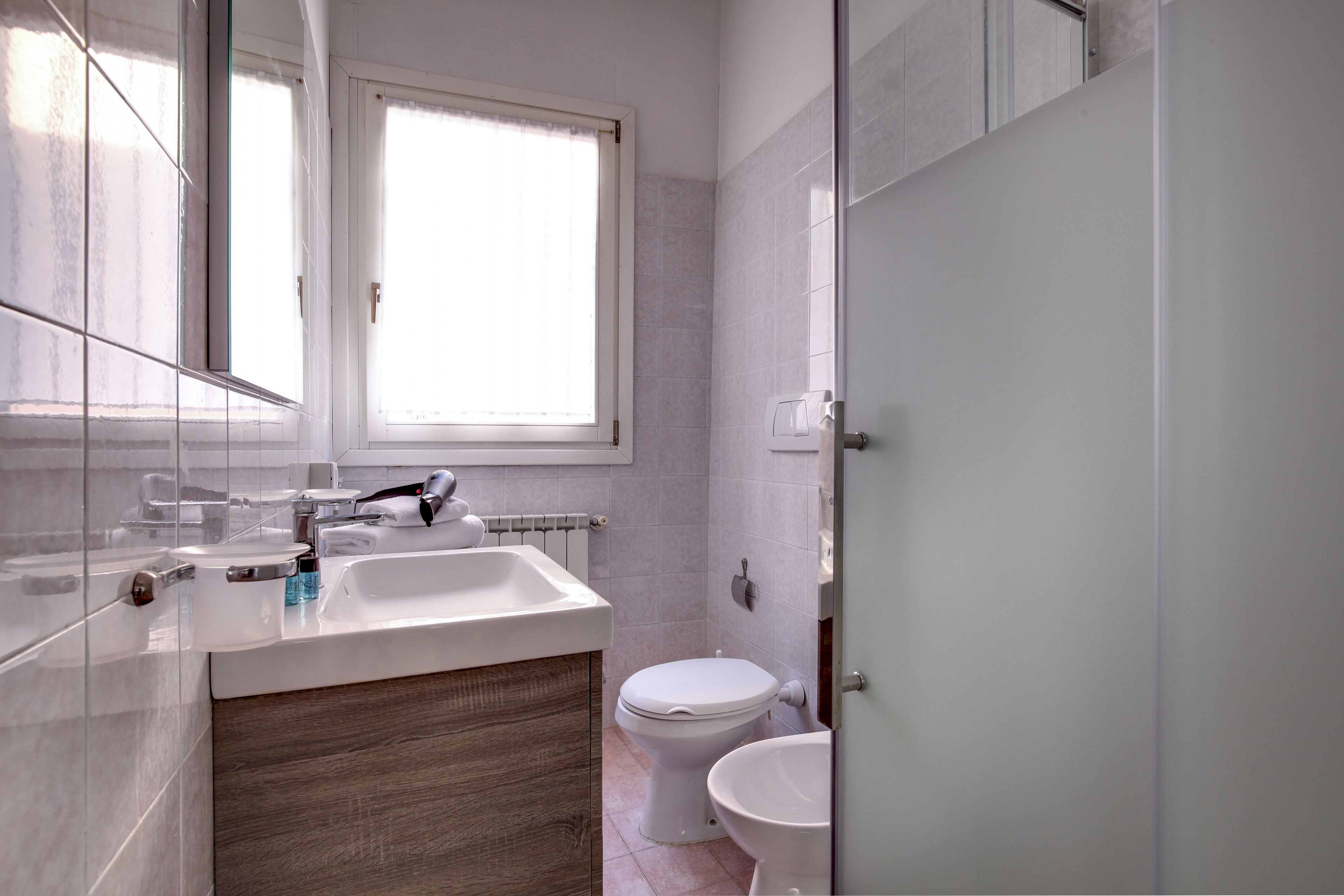 Un baño moderno con lavamanos, espejo y retrete blancos.