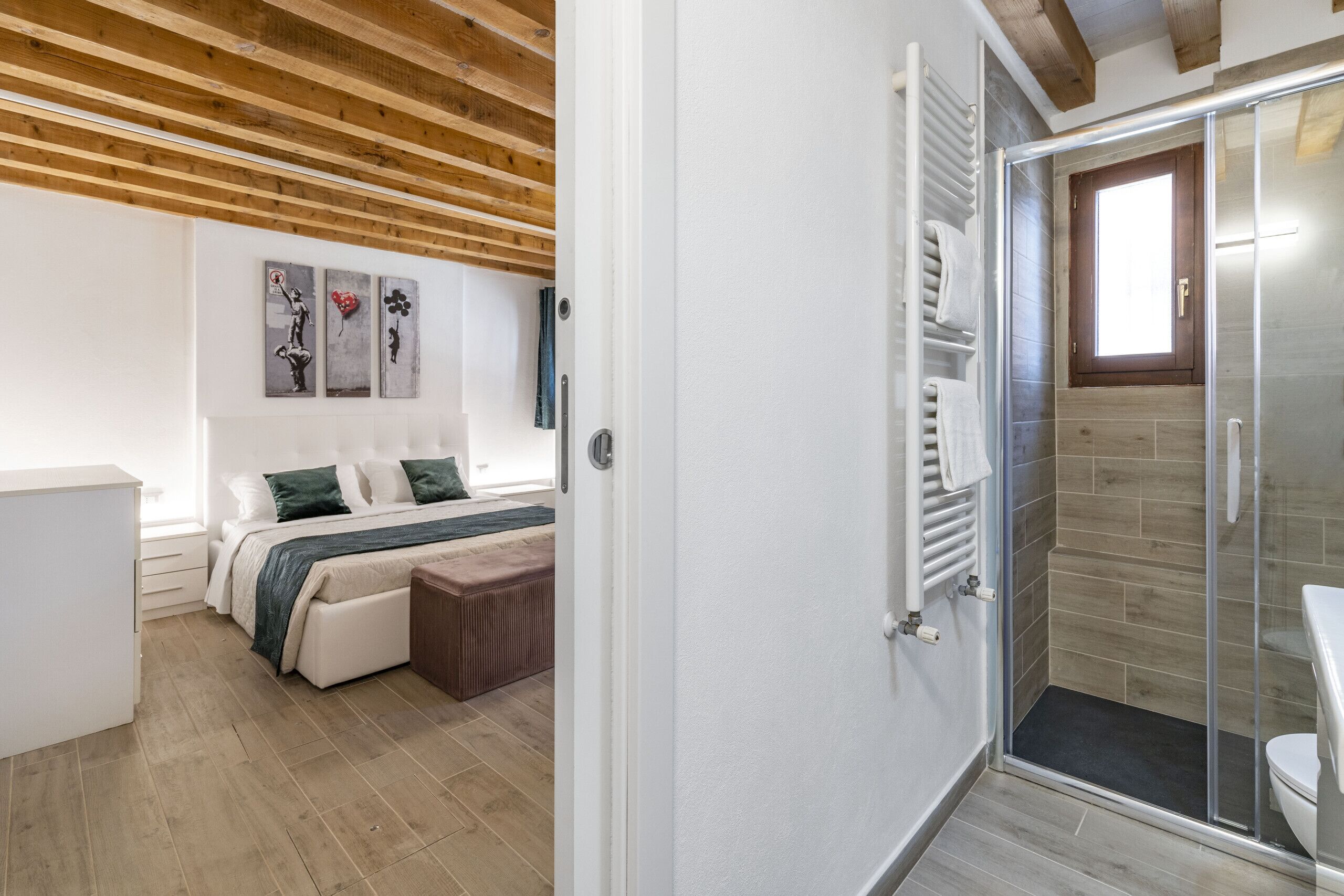 Un dormitorio con cama, un banco y zona de ducha con puerta de cristal.