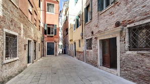 Una estrecha calle empedrada flanqueada por edificios históricos con paredes de ladrillo visto y contraventanas tradicionales.