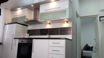 A modern kitchen with white cabinetry, a black countertop, and a built-in oven.
