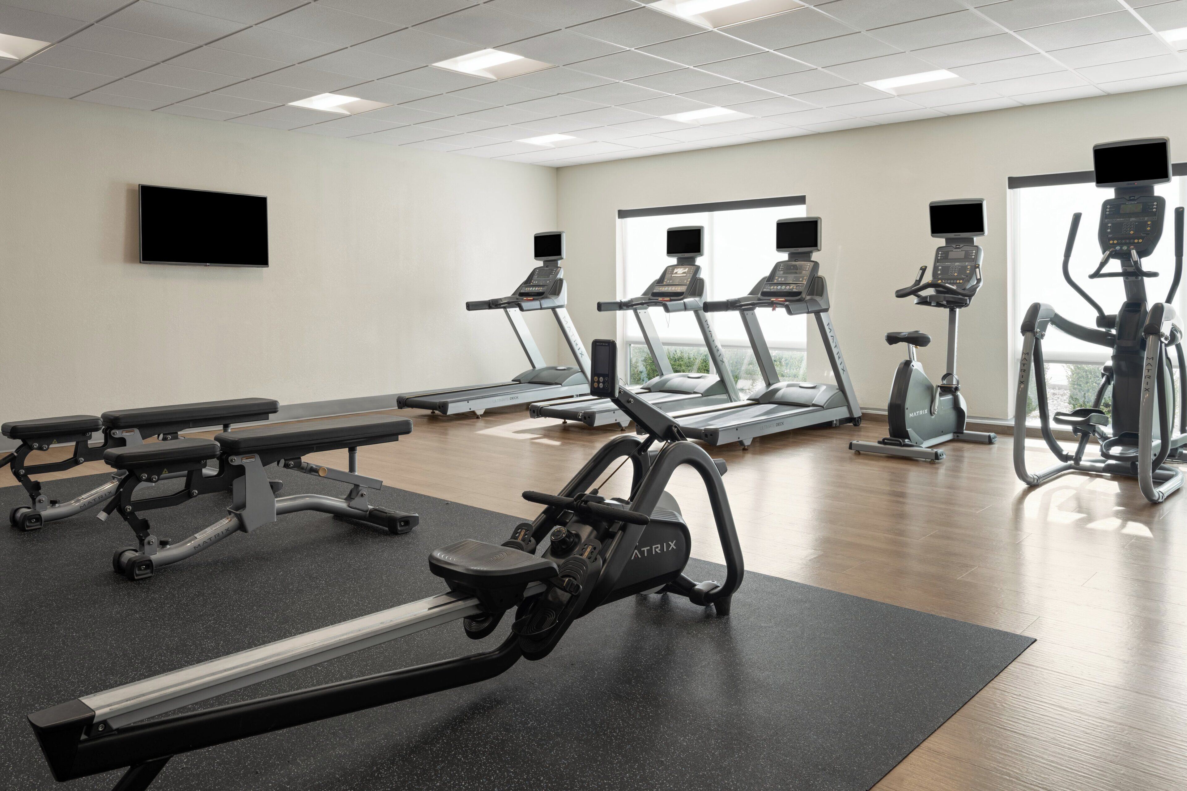 Un gimnasio con cintas de correr, elípticas y bancos.