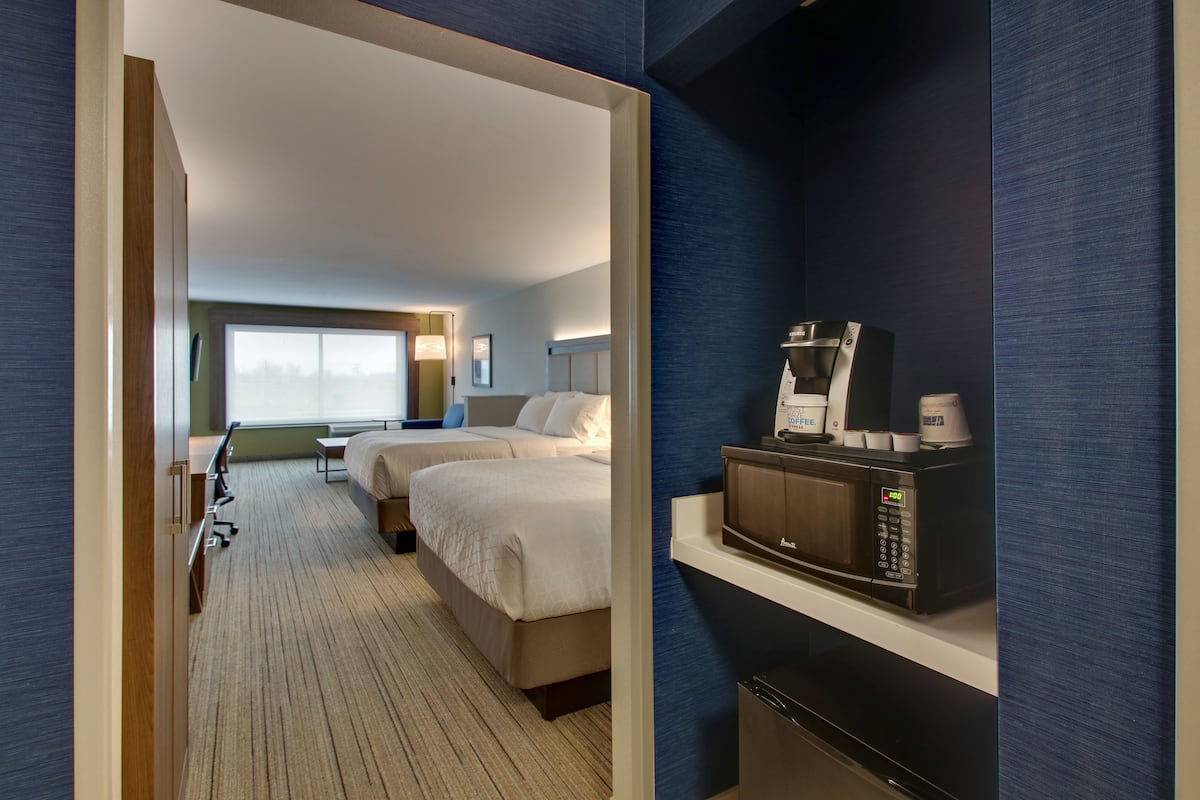 Ein Hotelzimmer mit zwei Betten, einer Mikrowelle und einer Kaffeemaschine auf einem Regal.