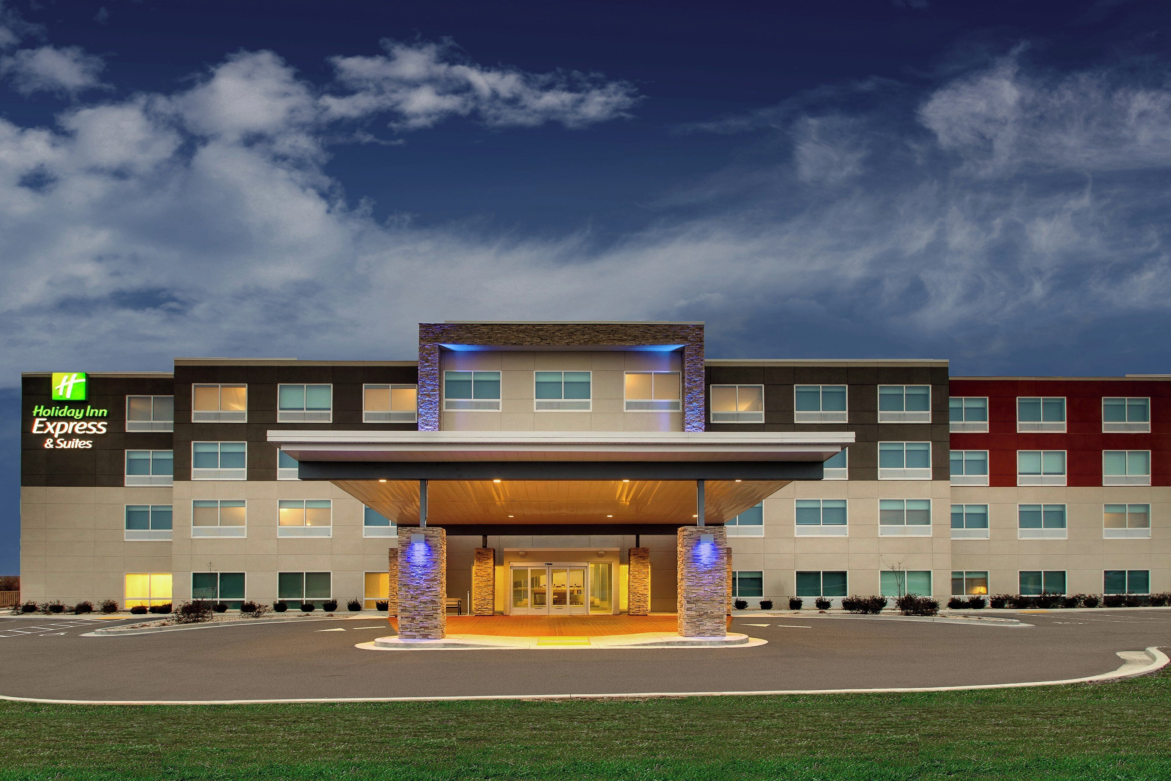 Un hotel Holiday Inn Express & Suites con un diseño moderno, que presenta una entrada cubierta y varios pisos.