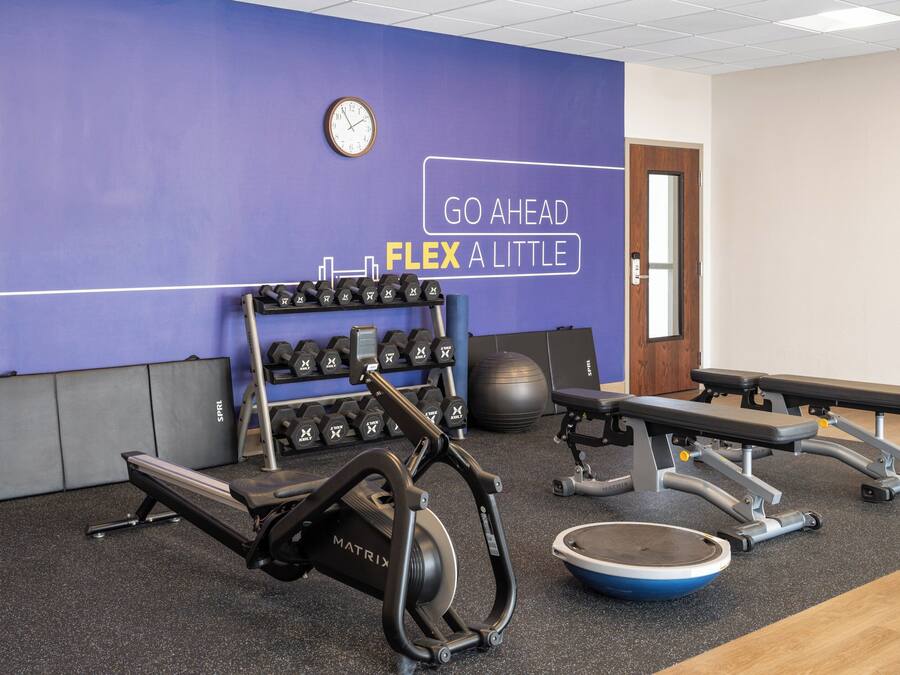 A gym with exercise equipment, a wall clock, and motivational text.