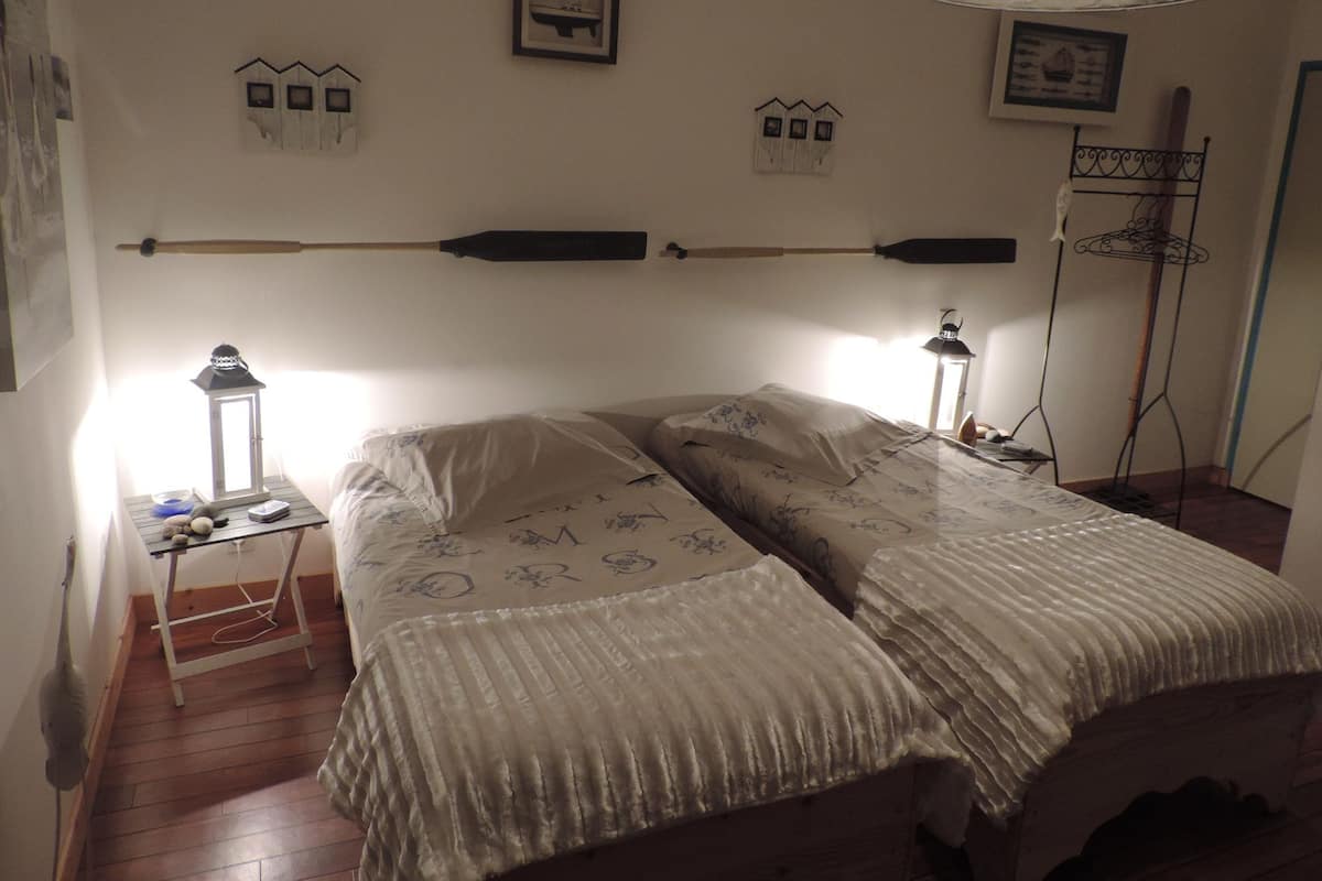 A bedroom with a bed, bedside tables, a lamp, and wall decorations.
