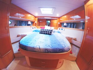 A compact, well-lit bedroom with a bed, bedside tables, and a ceiling light.