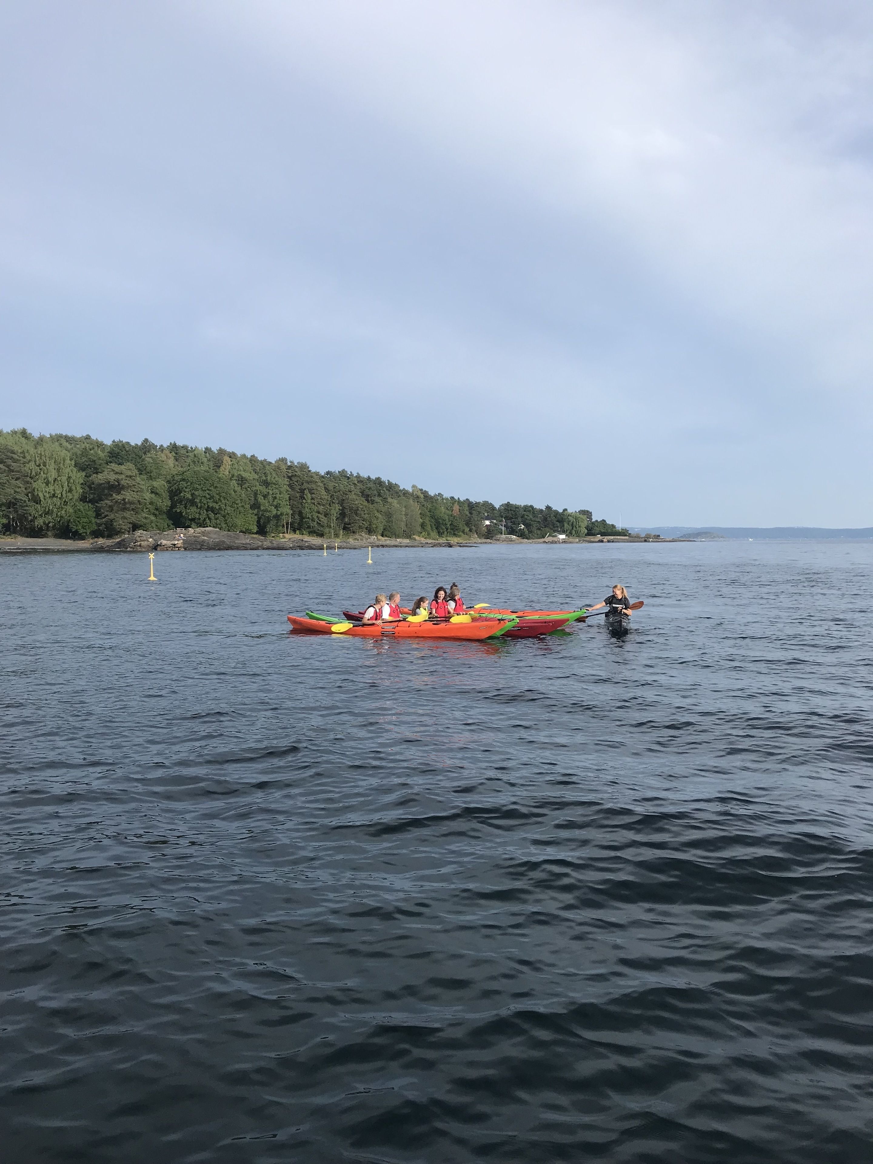 Un grupo de personas en una canoa sobre aguas tranquilas, con una orilla boscosa al fondo.