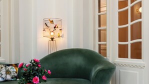 Un sofá verde, una mesita redonda con un florero y una lámpara de pared.