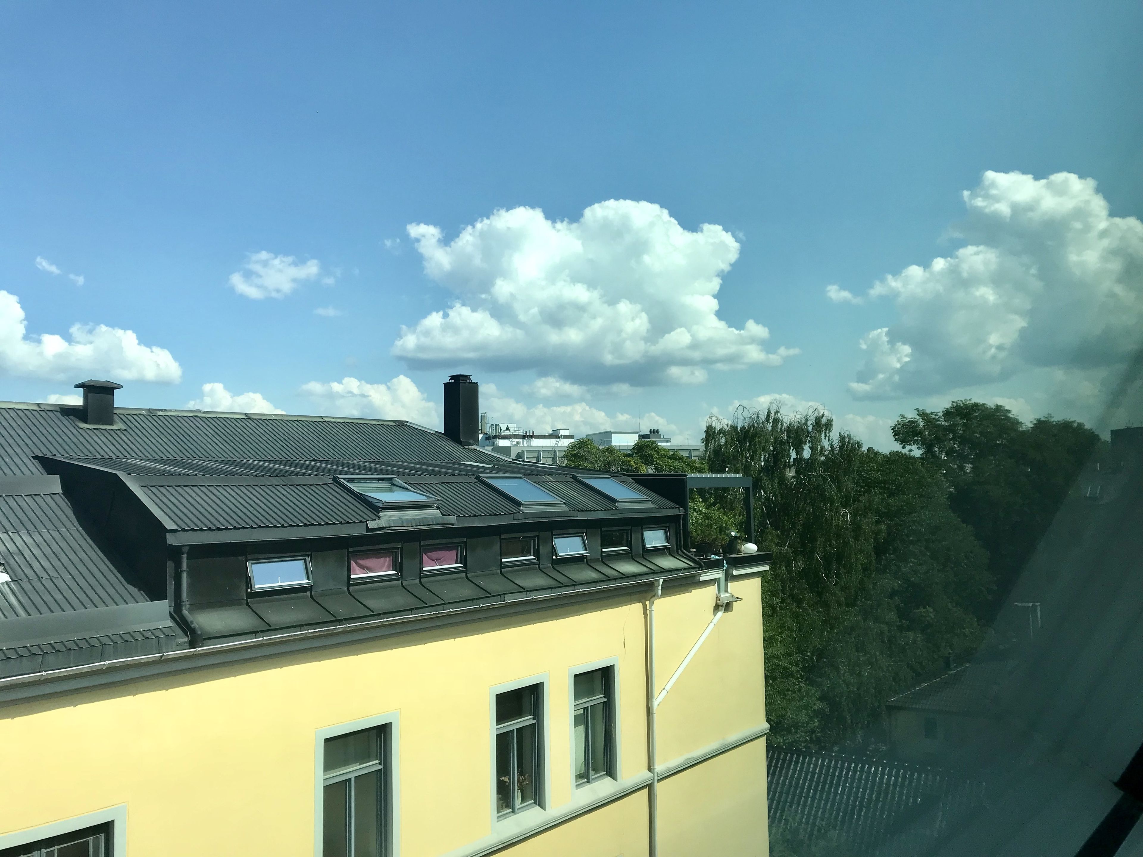 A building with a yellow facade, multiple skylights, and a flat roof with solar panels.