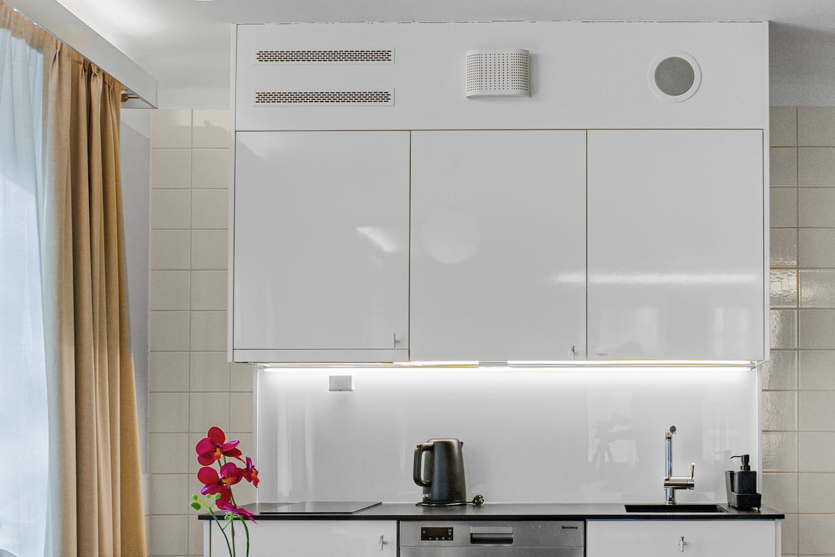 A modern kitchen with white cabinets, a stainless steel dishwasher, and a round dining table with white chairs.