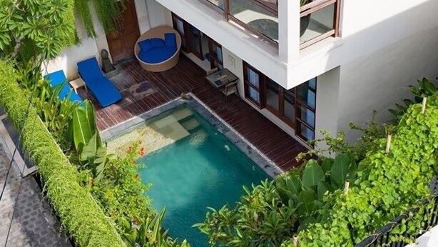 Ein modernes Gebäude mit Pool auf dem Dach, Außenbereich mit Sitzgelegenheiten und üppiger Bepflanzung.