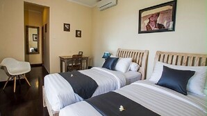 Ein Hotelzimmer mit zwei Betten, einem Schreibtisch, einem Stuhl und einem gerahmten Bild an der Wand.