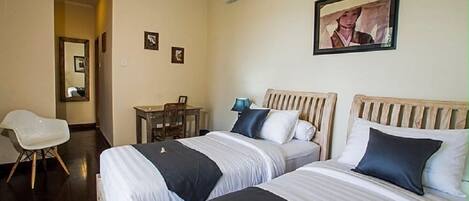 A hotel room with two beds, a desk, a chair, and a framed picture on the wall.