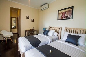 A hotel room with two beds, a desk, a chair, and a framed picture on the wall.