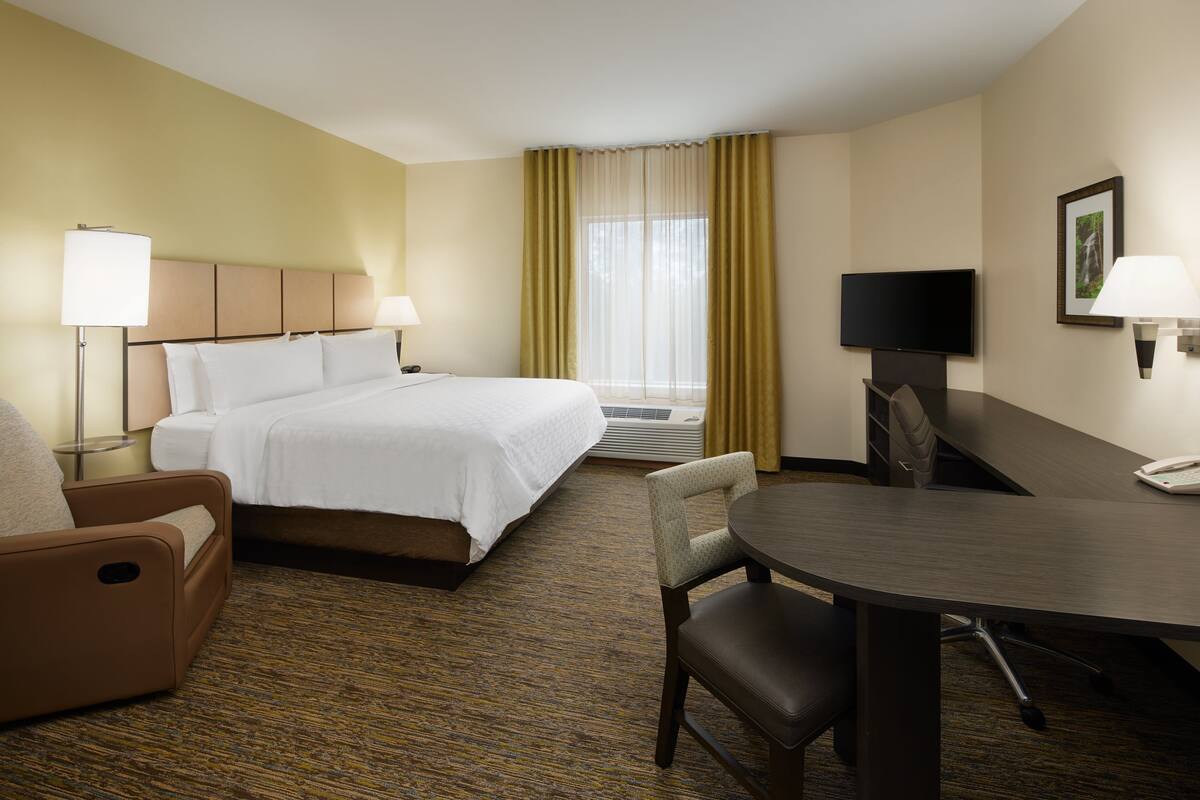 Une chambre d’hôtel équipée d’un lit, d’un bureau, d’une chaise, d’une télévision et d’une lampe.