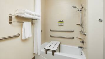 Un baño con una bañera blanca, barras de apoyo, cabezal de ducha y un perchero para toallas.