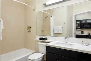 Ein modernes Badezimmer mit Badewanne, Toilette, Waschbecken und einem großen Spiegel.
