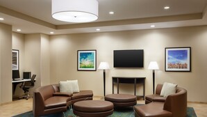 Habitación de hotel moderna con sofás de cuero marrón, un televisor de pantalla plana y dos cuadros en la pared.