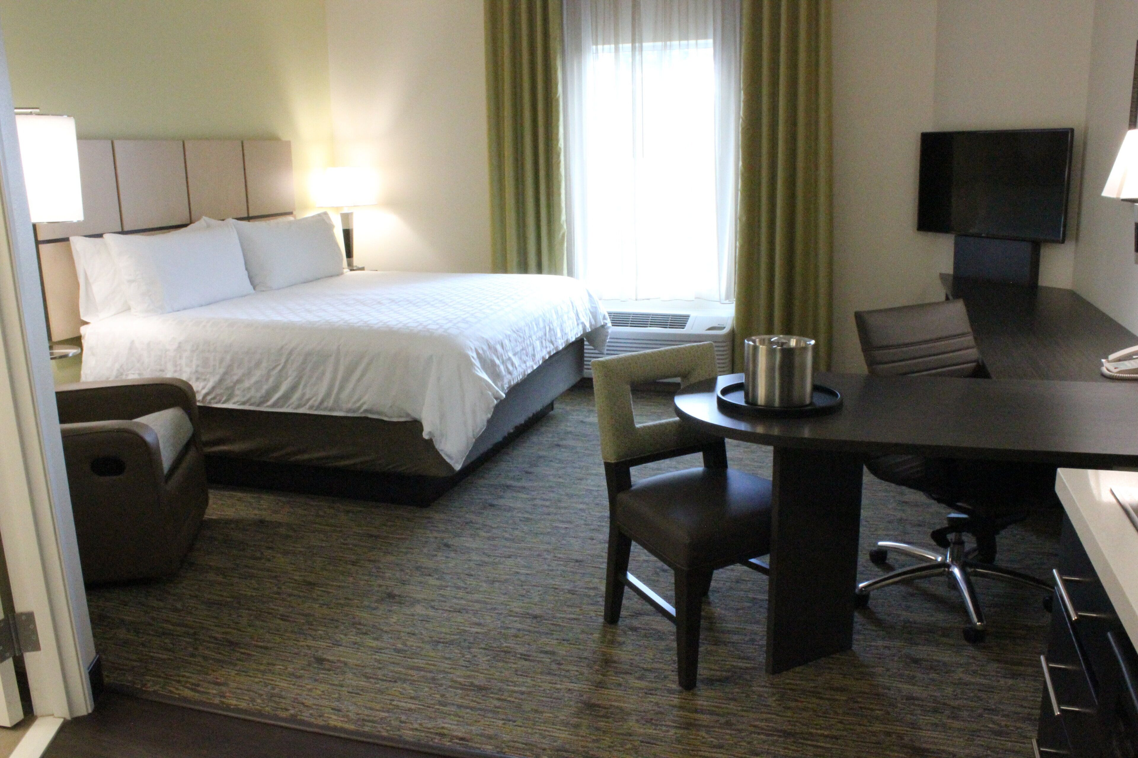 A hotel room with a bed, a desk, a chair, and a television.
