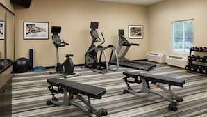 A gym with treadmills, elliptical machines, and weight benches.