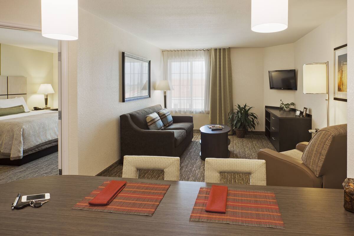 Une chambre d’hôtel comprenant un lit, un canapé, une télévision, un bureau avec deux chaises et une table à manger.