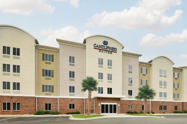 Un hotel de varios pisos con un llamativo letrero de "Candlewood Suites", que presenta fachada de ladrillo y numerosas ventanas.
