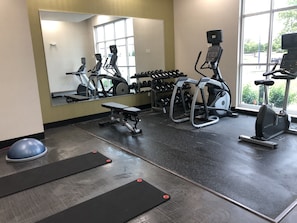 A gym with exercise equipment, a bench, and a large mirror. - Holiday Inn & Suites Memphis Southeast-Germantown by IHG (Memphis)