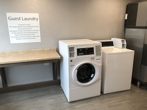 A guest laundry area with a washing machine and dryer, a bench, and a sign with operating instructions. - Holiday Inn & Suites Memphis Southeast-Germantown by IHG (Memphis)