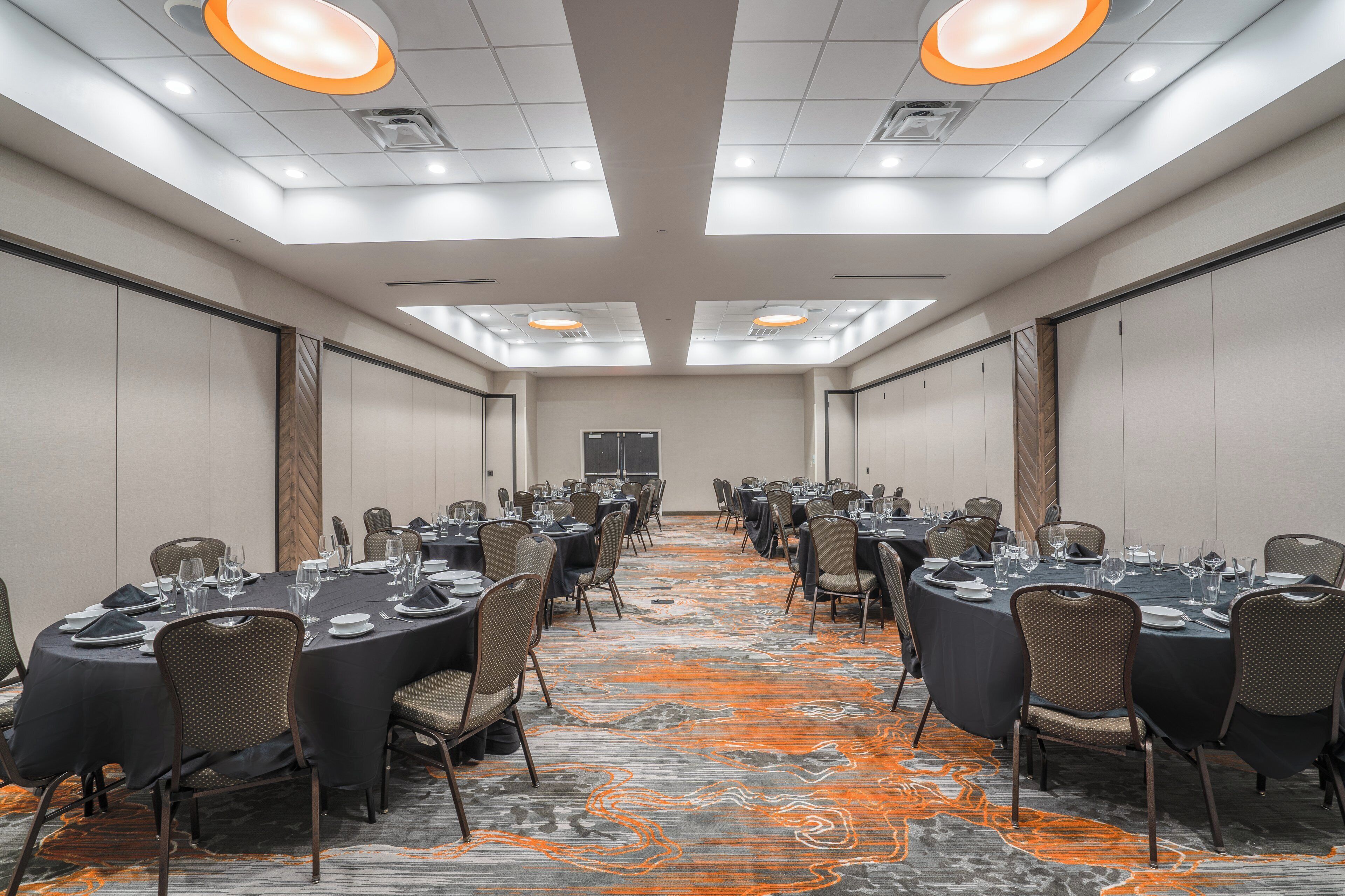 A conference room with round tables, chairs, and a carpeted floor.