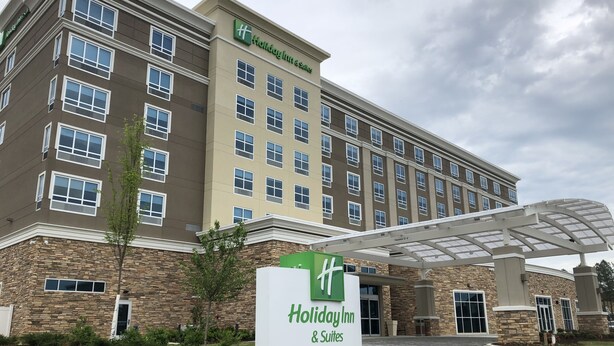 A Holiday Inn & Suites building with a stone facade, multiple windows, and a covered entrance area. - Holiday Inn & Suites Memphis Southeast-Germantown by IHG (Memphis)