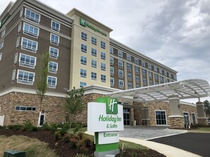 A Holiday Inn & Suites building with a stone facade, multiple windows, and a covered entrance area. - Holiday Inn & Suites Memphis Southeast-Germantown by IHG (Memphis)