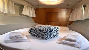 A circular bed with a patterned ottoman, white linens, and curtains. - Yacht Suite Castiglione della Pescaia (Castiglione della Pescaia)