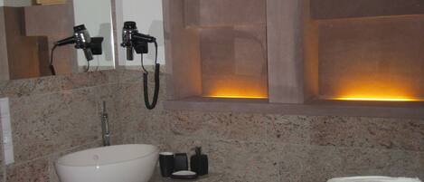 Ein Badezimmer mit Waschbecken, Spiegel, Handtuchhalter und einem Fenster mit Jalousien.