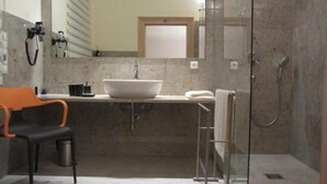 Ein modernes Badezimmer mit großem Spiegel, Waschbecken, Dusche und Stuhl.