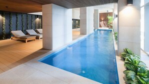 A modern indoor swimming pool with lounge chairs and a wooden ceiling. - The Escape in Southern Cross Station (Melbourne)