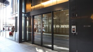 A modern building with large glass doors, a sign for "The Fifth Apartments," and a fire hydrant labeled "Fire Hydrant." - The Escape in Southern Cross Station (Melbourne)