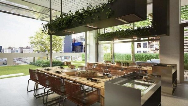 A modern dining area with a long table, chairs, and a kitchen counter. - The Escape in Southern Cross Station (Melbourne)