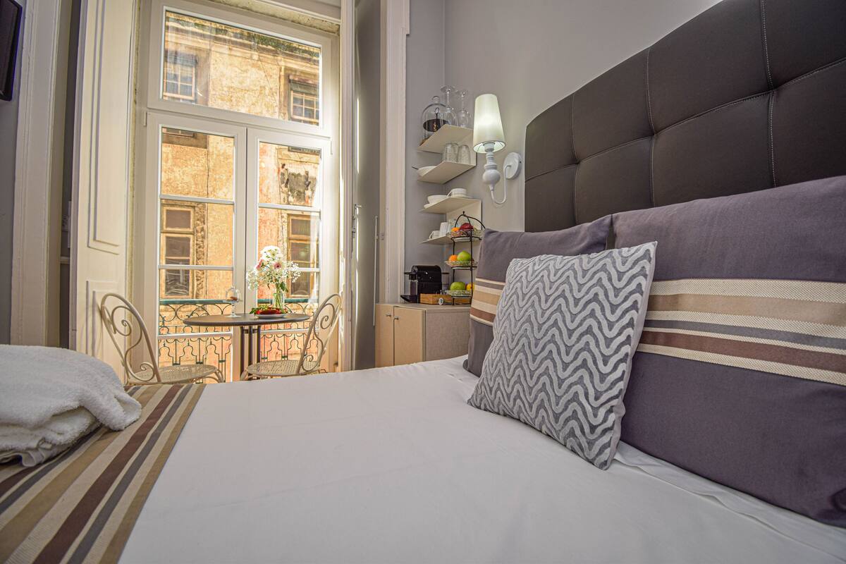 Ein Hotelzimmer mit Bett, Balkon, Esstisch und Blick ins Freie.