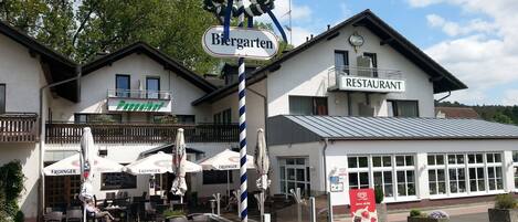 Un restaurante con terraza, un letrero que dice 'Biergarten' y un cartel con la palabra 'RESTAURANT'.