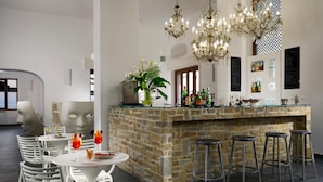 A modern kitchen with a stone island, bar stools, and a chandelier. - Hotel La Playa (Pollica)