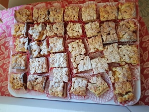 Una bandeja con postres cuadrados, posiblemente productos de repostería, dispuesta ordenadamente sobre un papel rojo.