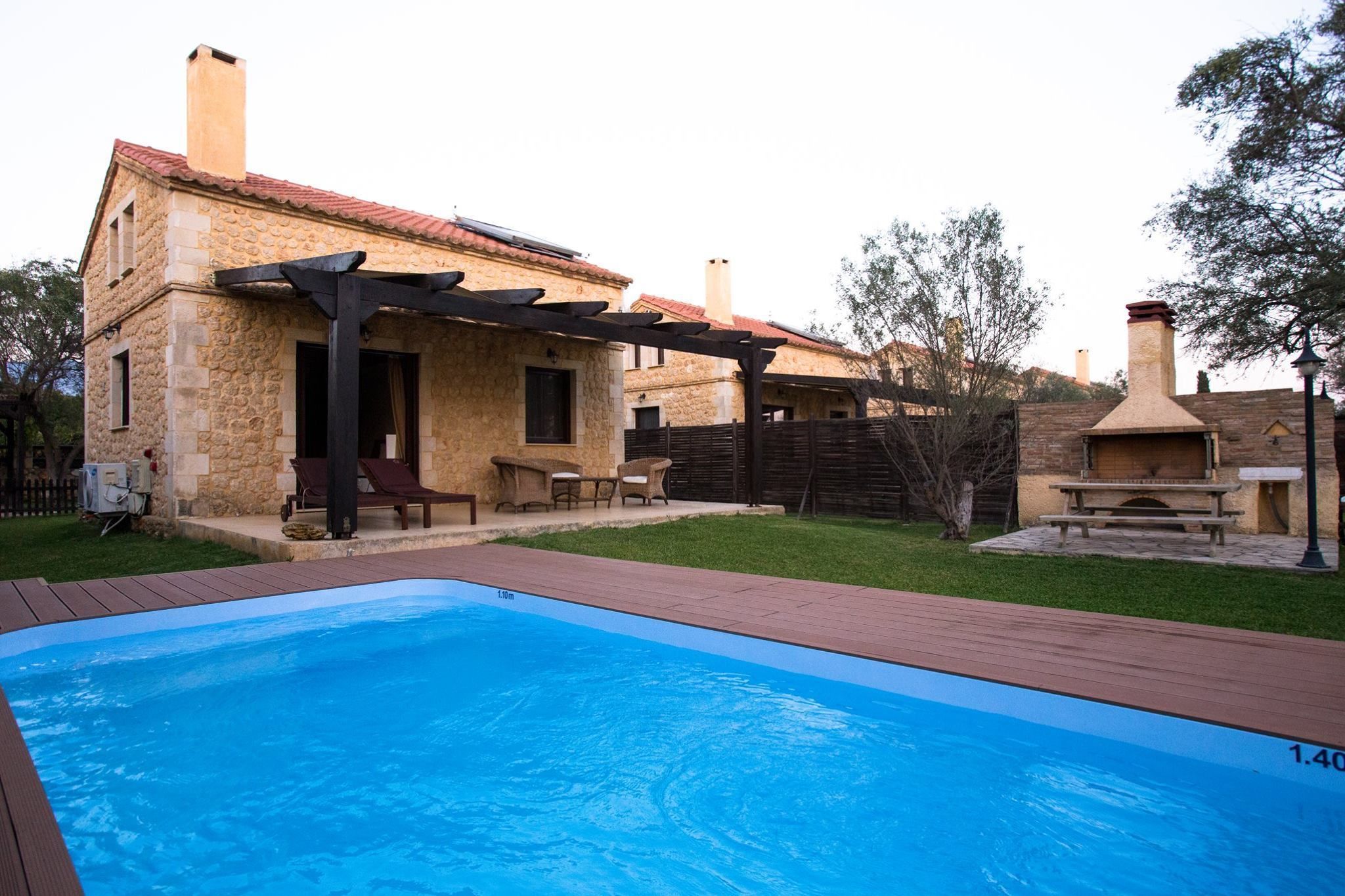 A stone building with a pool, outdoor seating, and a barbecue area.