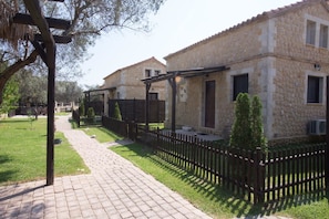 A stone building with a paved pathway and a wooden fence.