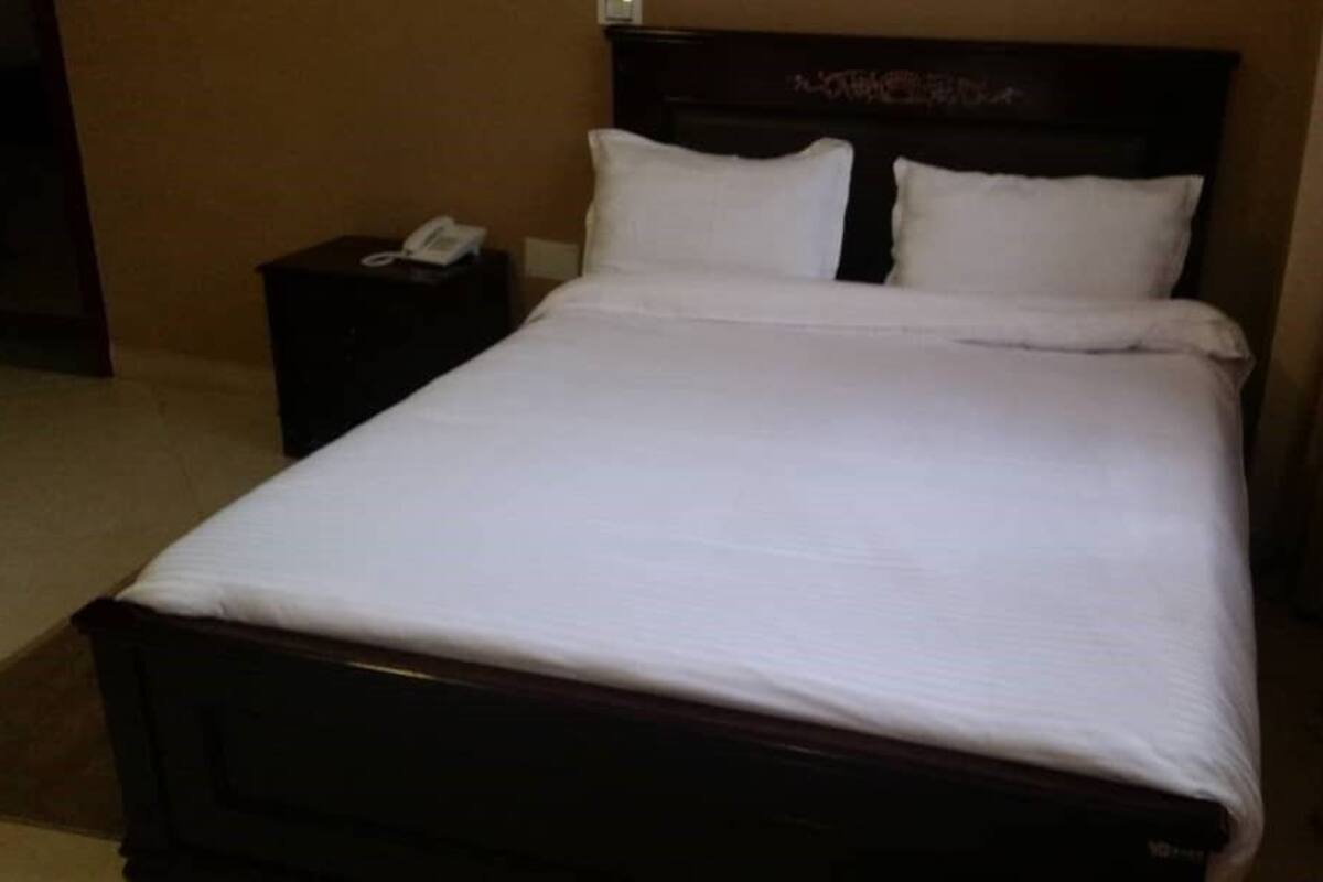 A neatly made bed with white linens in a hotel room.