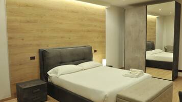 Ein modernes Schlafzimmer mit Holzvertäfelung, einem großen Bett mit weißer Bettwäsche, einem Nachttisch und einem Spiegel.
