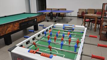A room with a foosball table, a pool table, and a ping pong table.